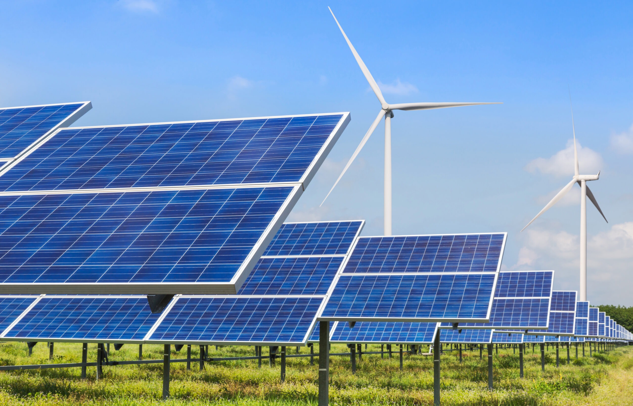 Solar panels and wind turbines are showcased in a renewable energy field, emphasizing sustainable power sources under a clear blue sky.