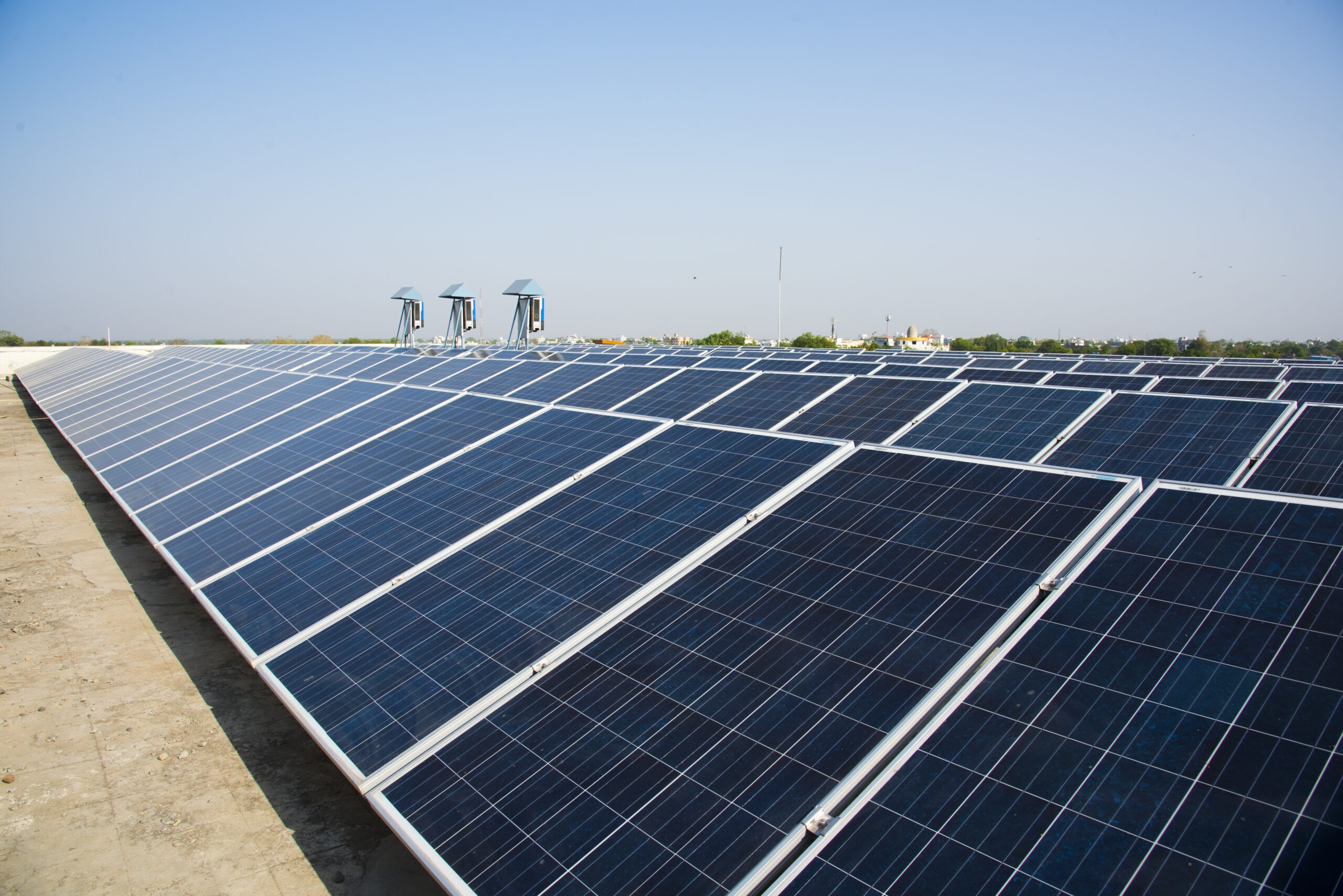 Solar panels installed on a rooftop harnessing sunlight for renewable energy, with clear skies and distant rooftops visible in the background.